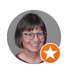 Portrait of a smiling person with glasses and a gray background, marked with an orange star badge