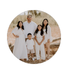 Family of five standing together outdoors in white outfits, smiling in a sandy desert setting