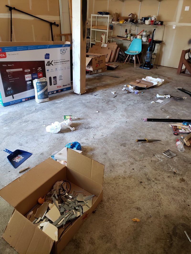 A messy garage with a box of junk on the floor.