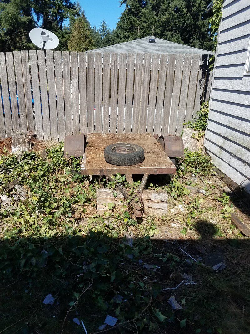 A wheelbarrow with a tire on it is sitting in front of a wooden fence.