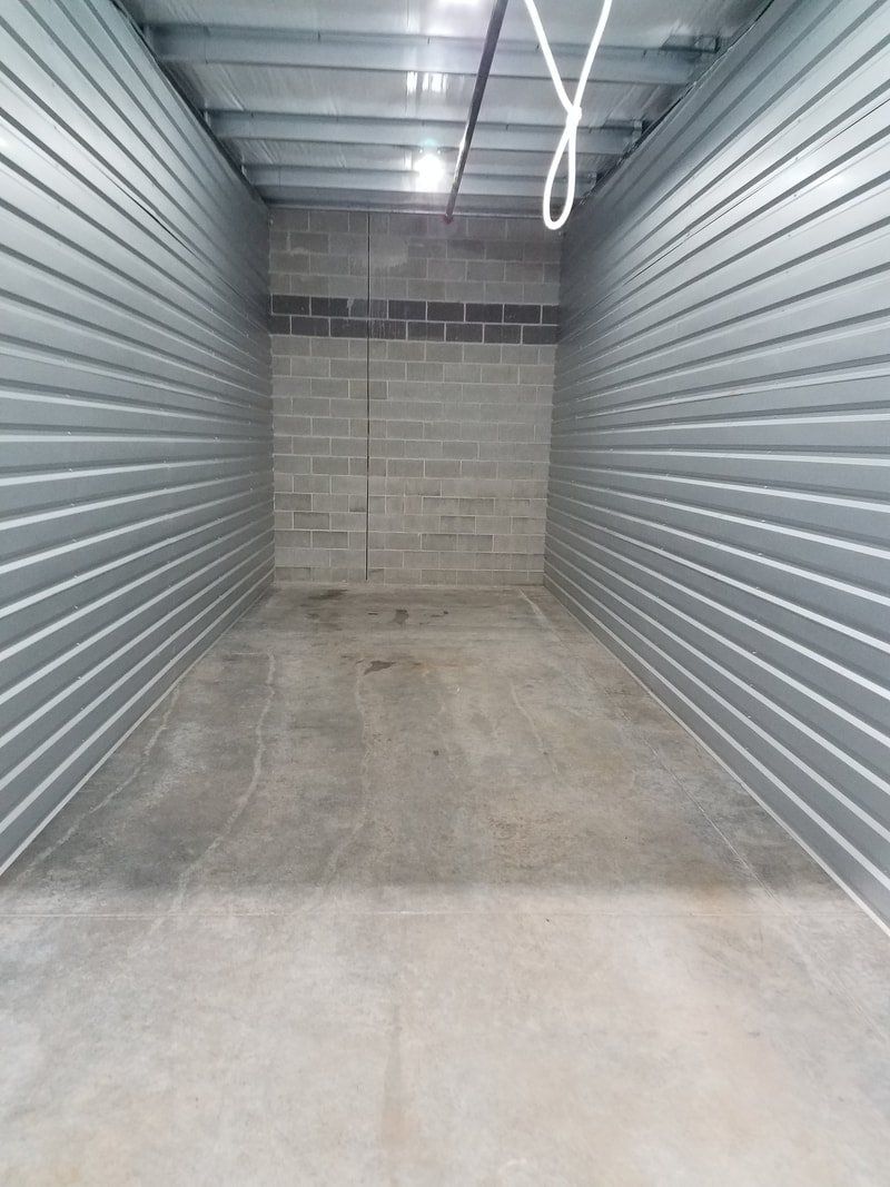 An empty garage with a concrete floor and brick walls.