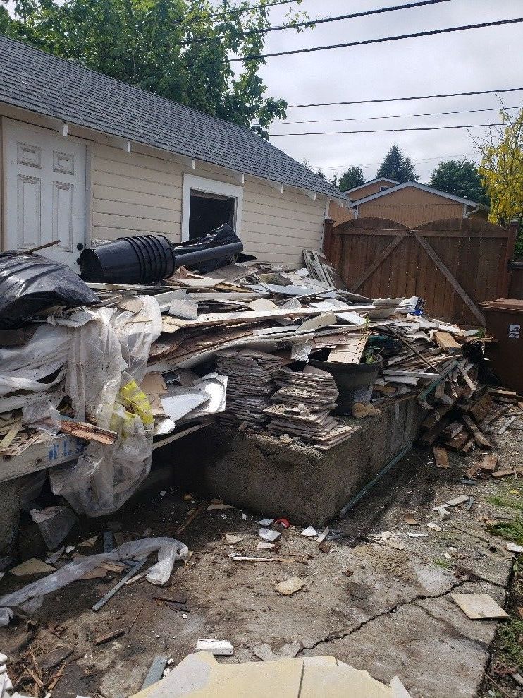 A wheelbarrow with a tire on it is sitting in front of a wooden fence.