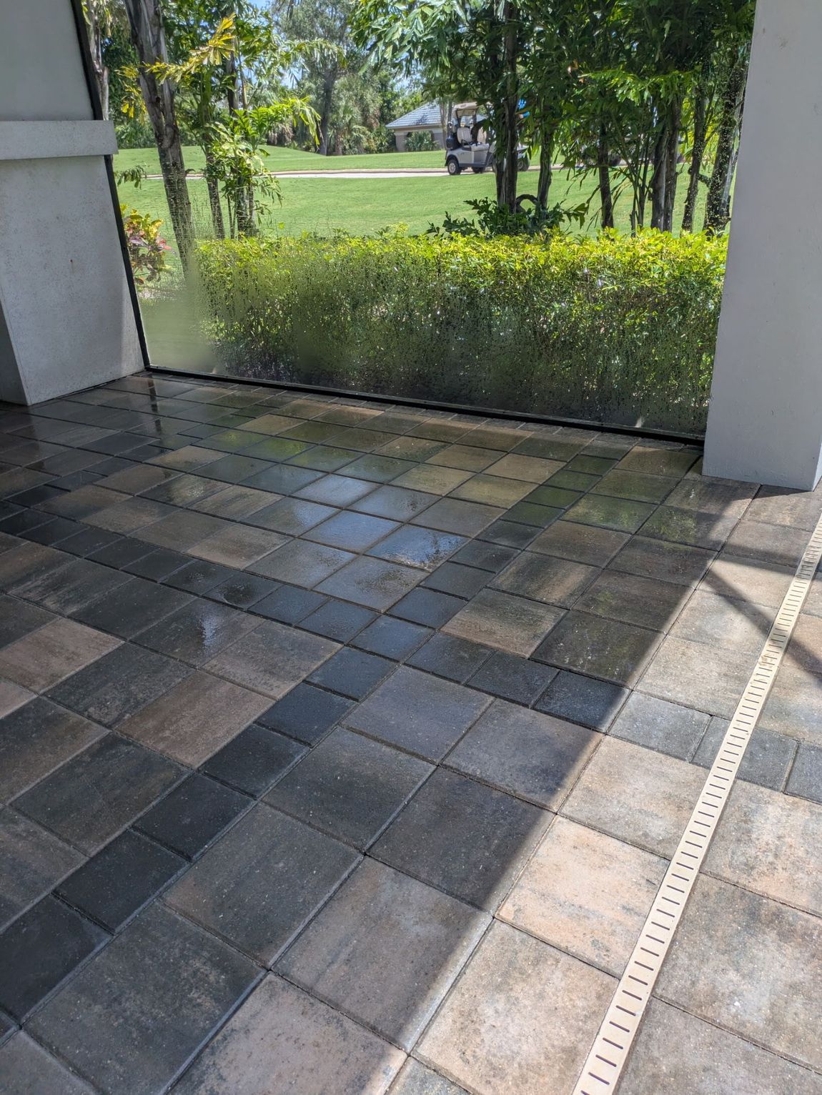 Patio with patterned pavers, screen enclosure, and view of greenery.