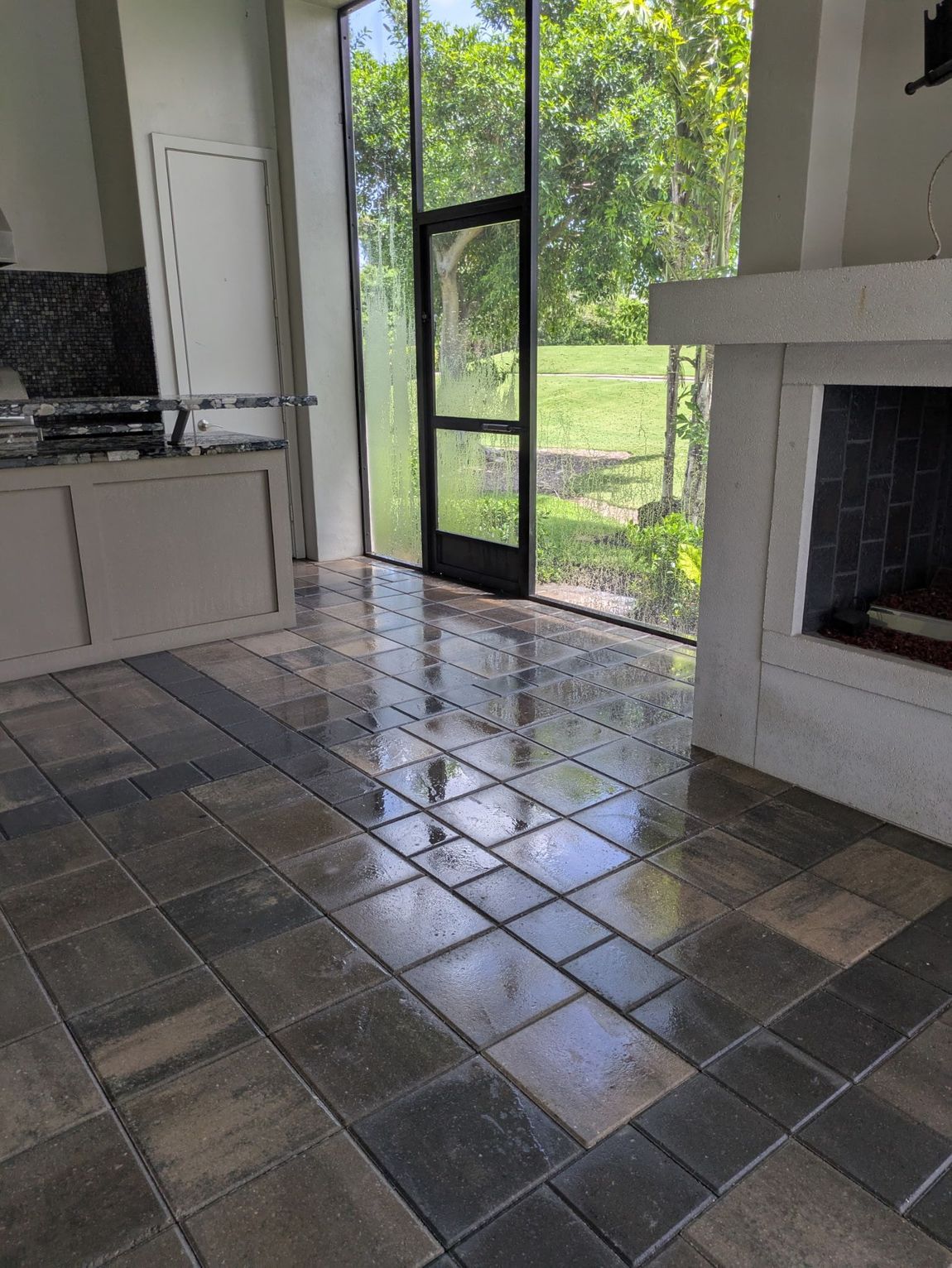 Tiled floor in a room with a screened door and fireplace, overlooking a green landscape.