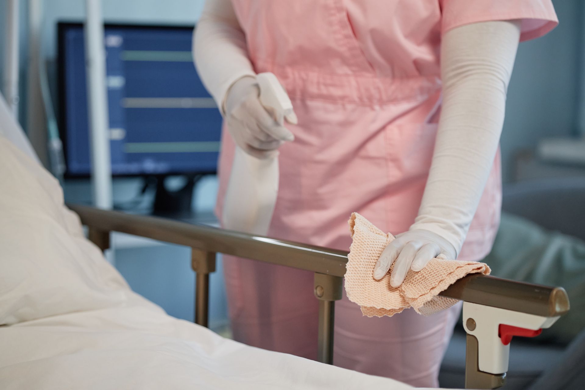 A nurse is cleaning the railing of a hospital bed.