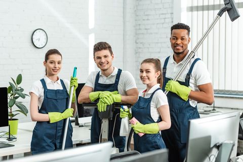 A group of cleaners are posing for a picture in an office.