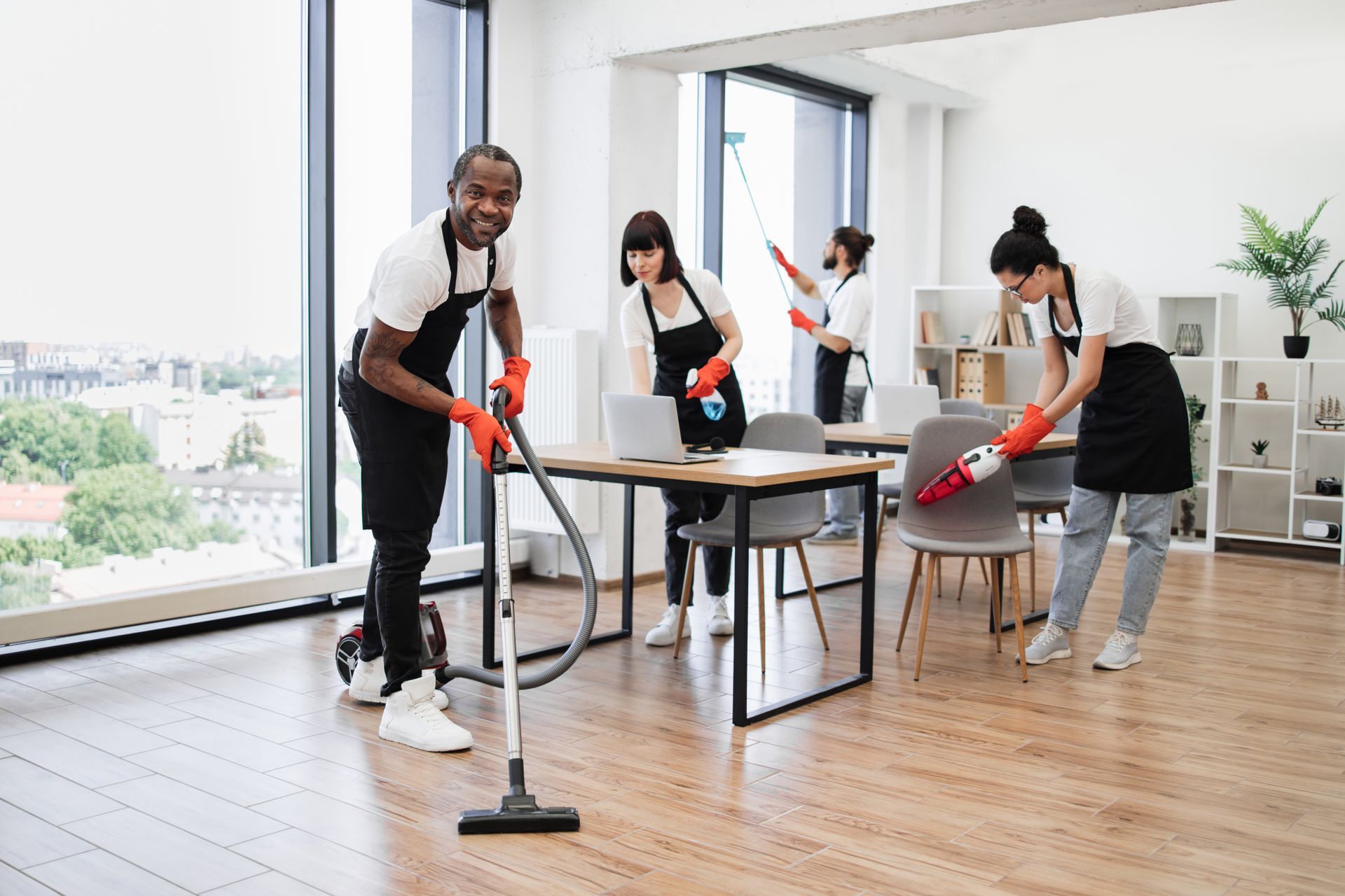 A group of people are cleaning an office with a vacuum cleaner.