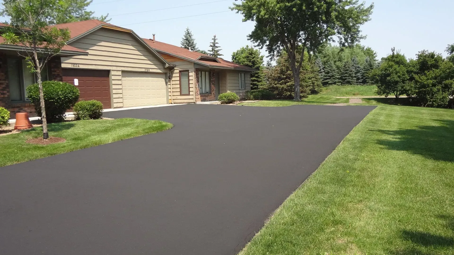 Two-story gray house with a driveway, garage, and blue sky background.