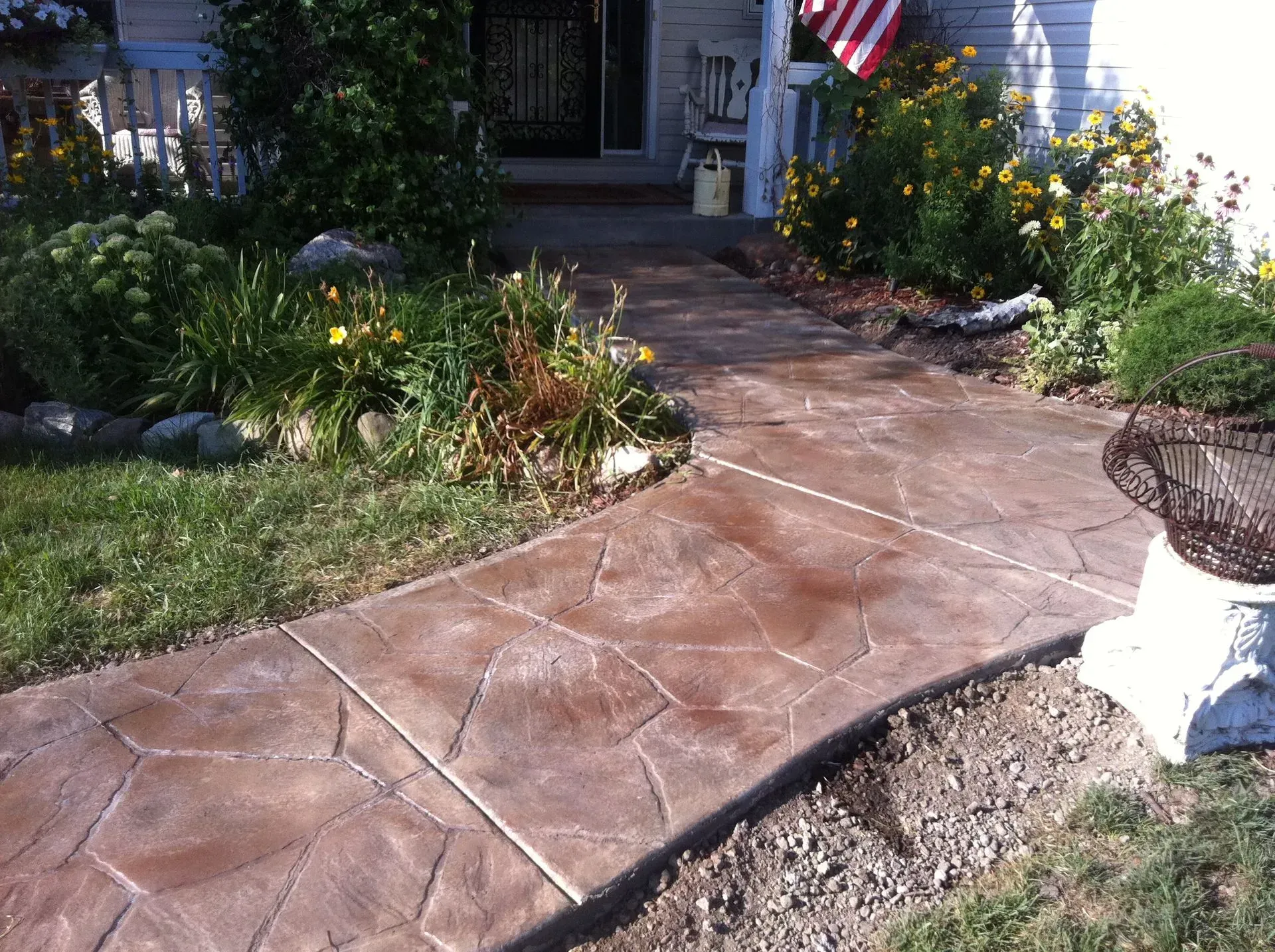 Brick-patterned walkway curves through a grassy lawn, sunlight glinting off its surface.