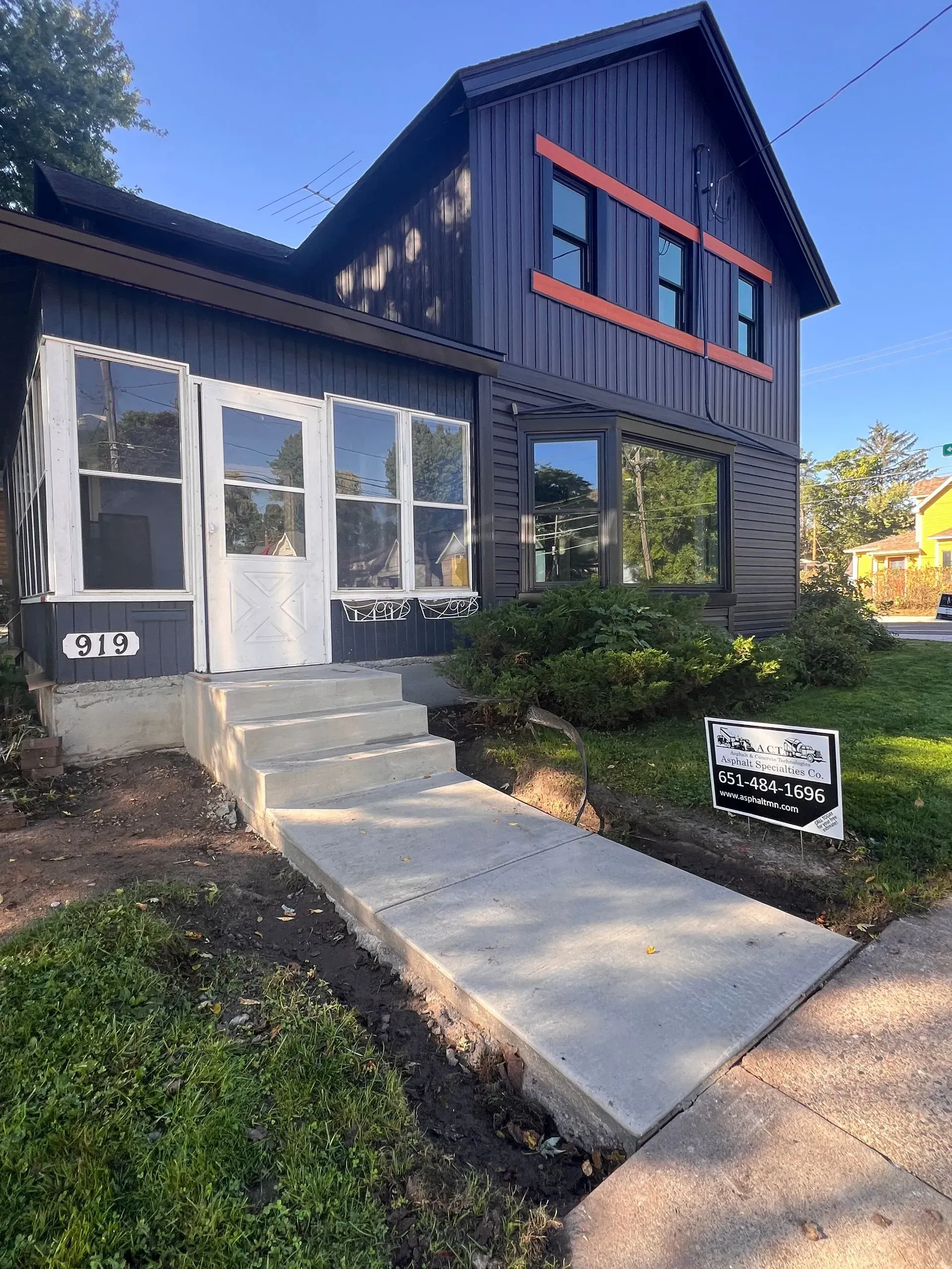 Backyard patio with pergola, seating, stone flooring, and grassy areas.