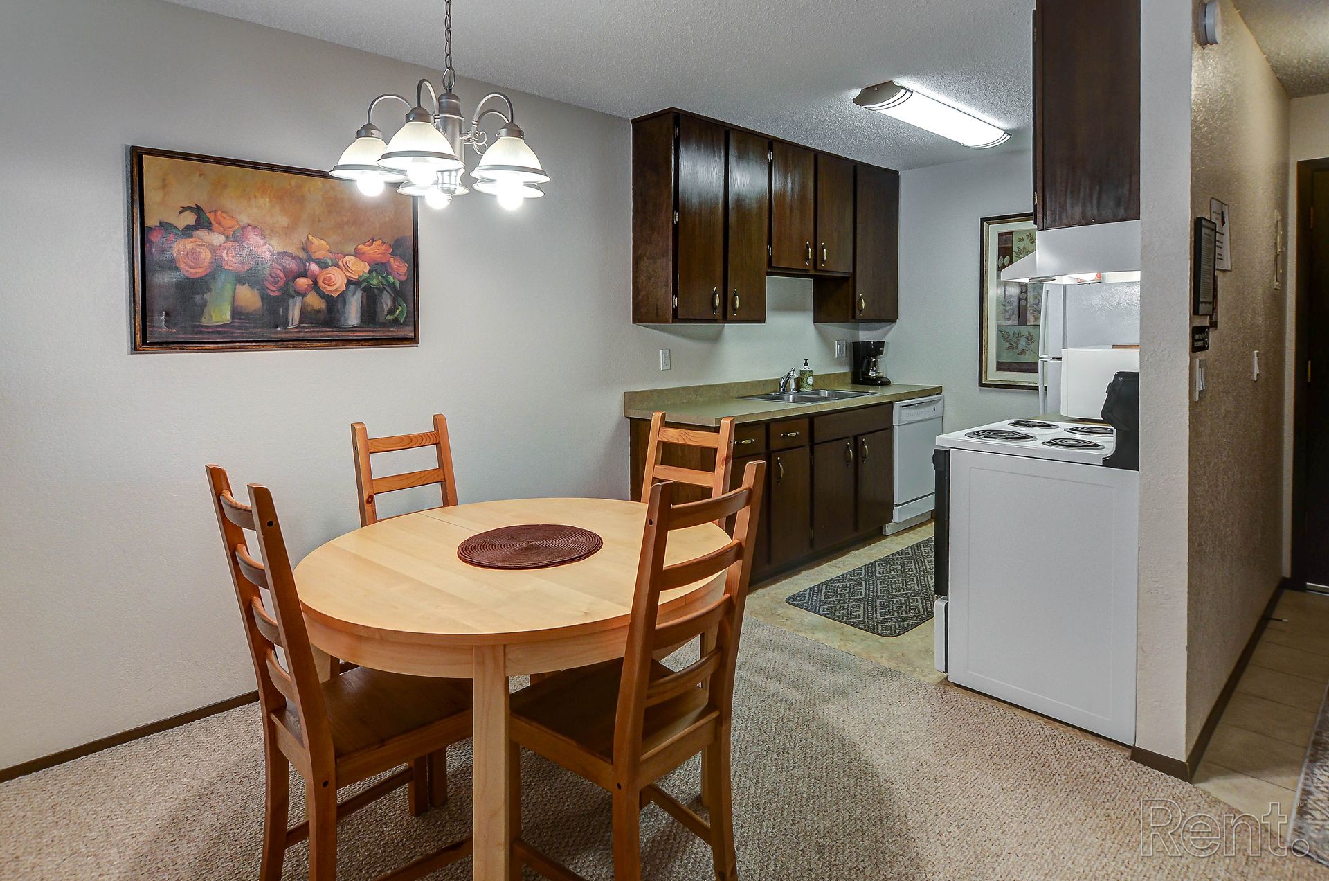 a kitchen with a table and chairs and a painting on the wall .