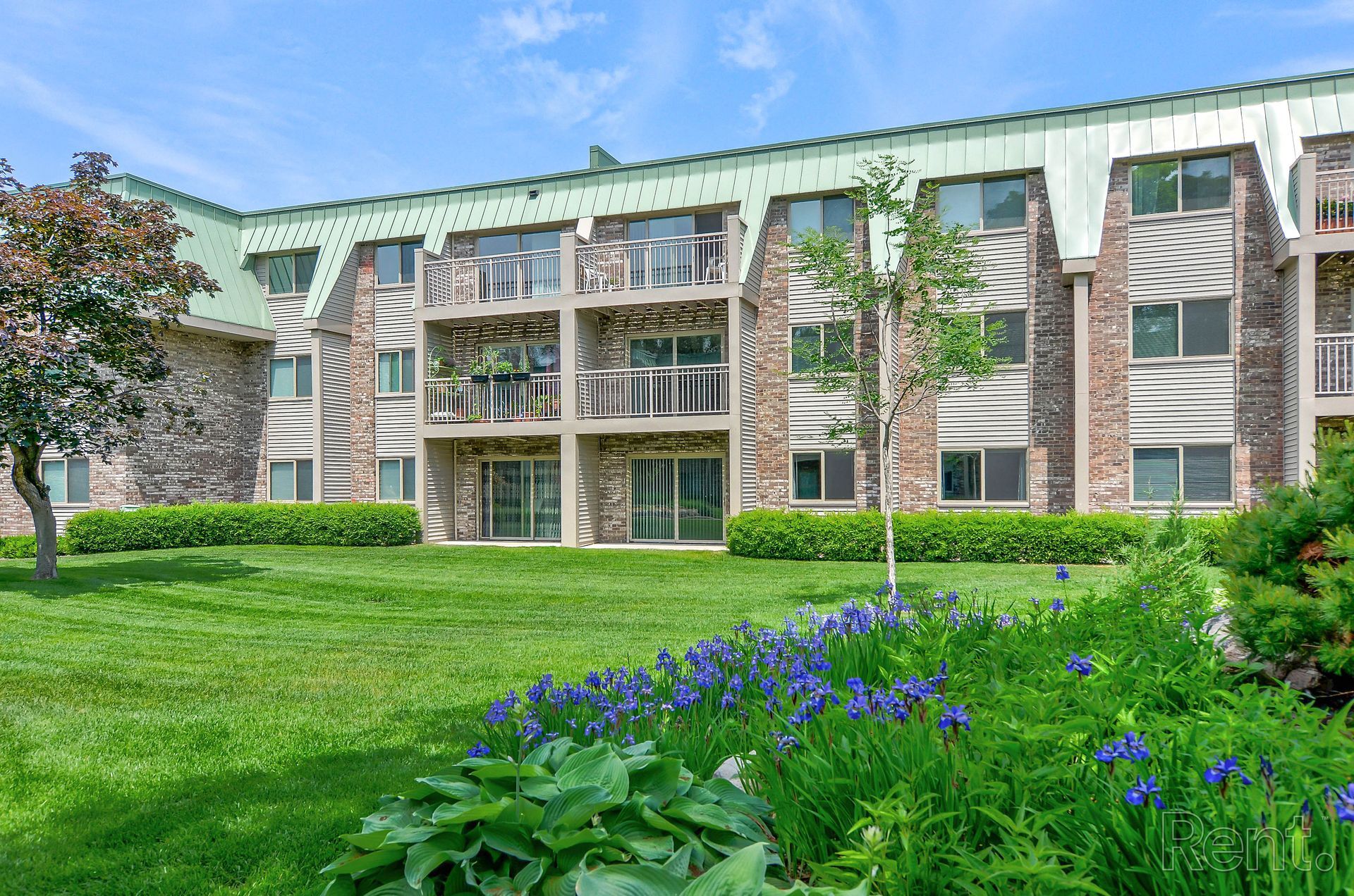 a large apartment building with a lush green lawn in front of it .