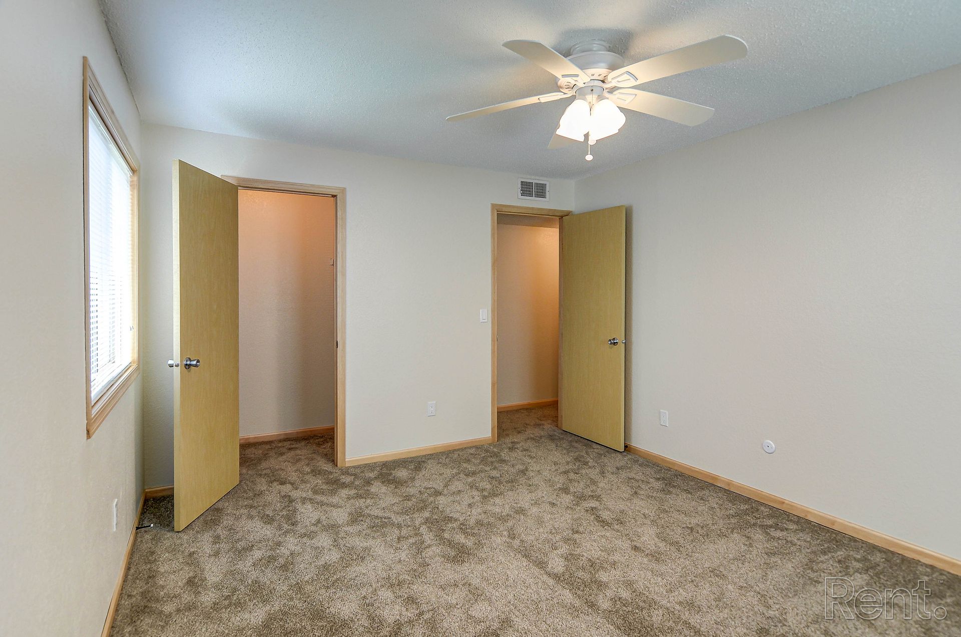 an empty bedroom with a ceiling fan and two doors
