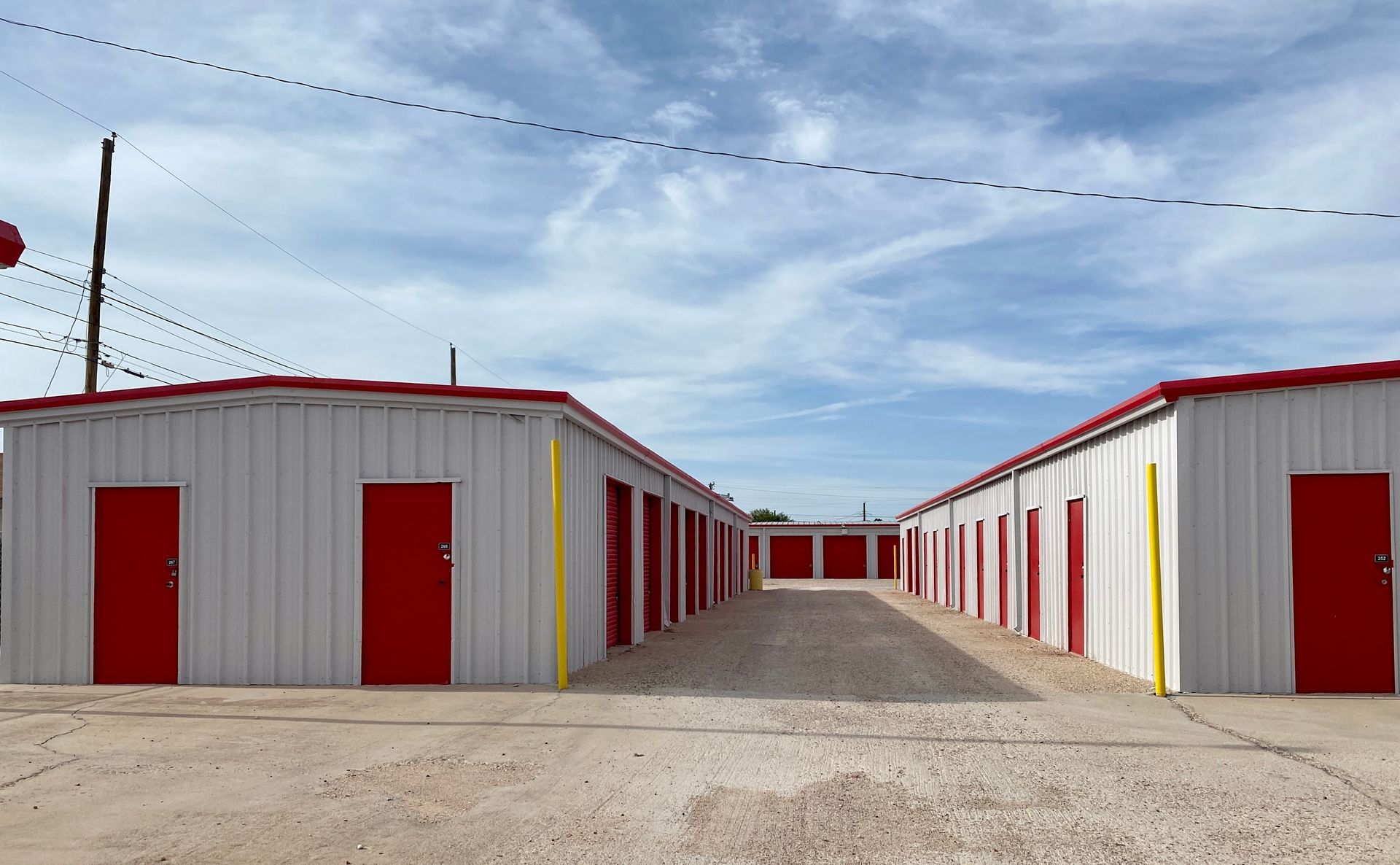 Outdoor storage facility in Hobbs, New Mexico, rows of red and white storage units under a clear blue sky