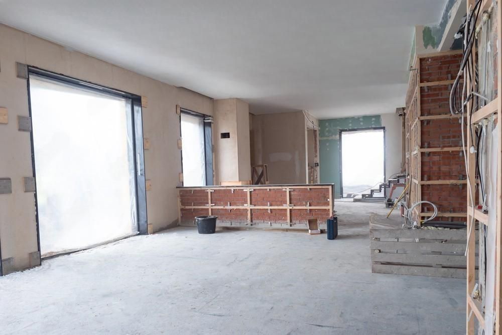 a kitchen under construction with white cabinets and wooden drawers