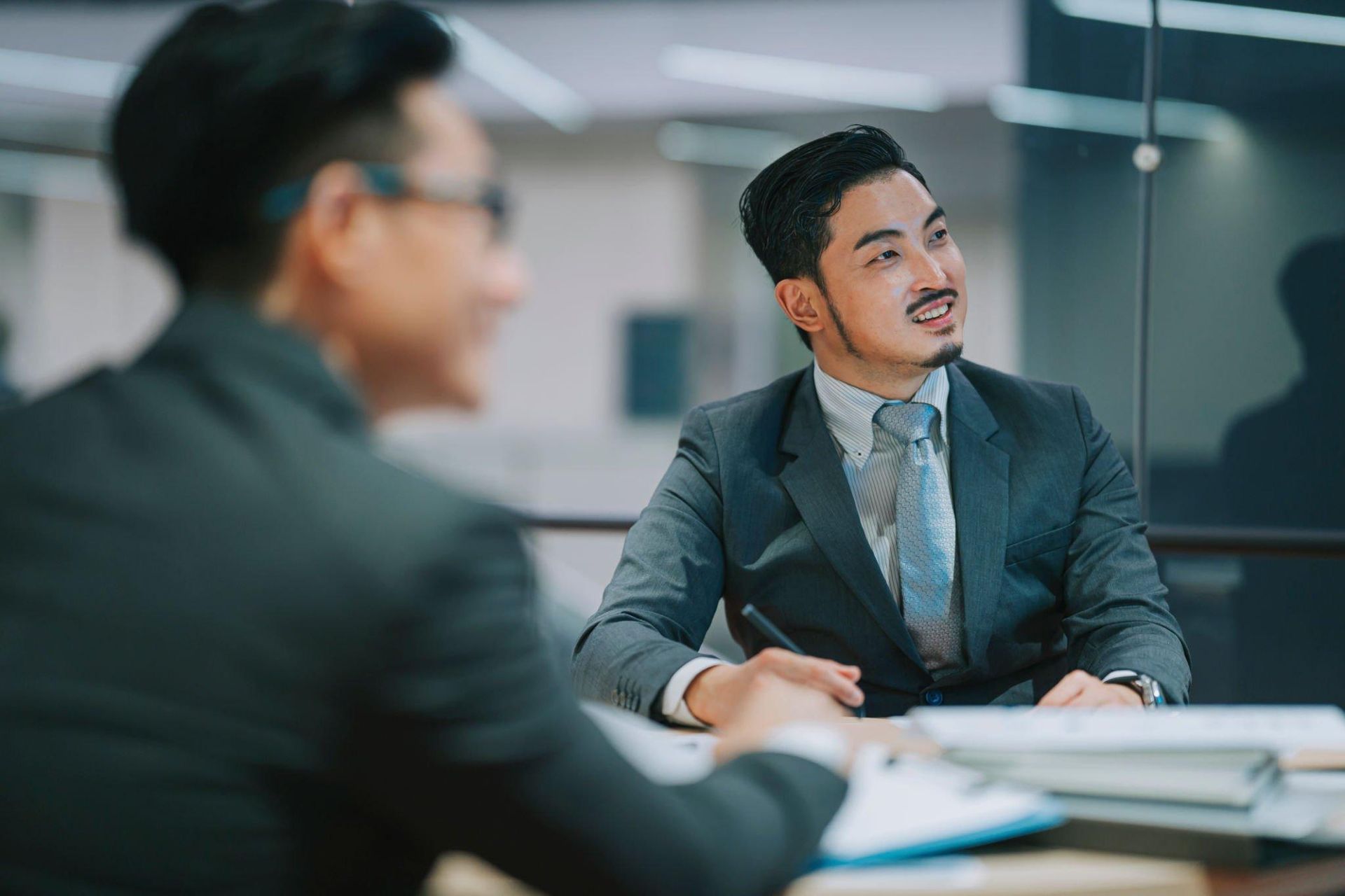 Two men in suits are sitting at a table having a meeting.