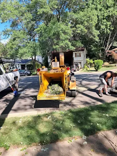 A tree chipper is sitting on the side of the road next to a truck.