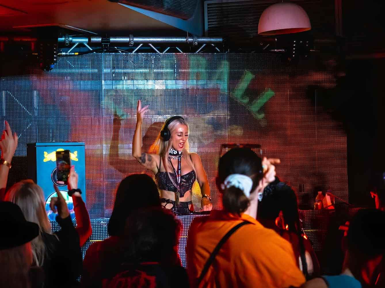 A Woman Is Standing In Front Of A Dj Booth Giving A Peace Sign — Celeste Agency in Sydney, QLD