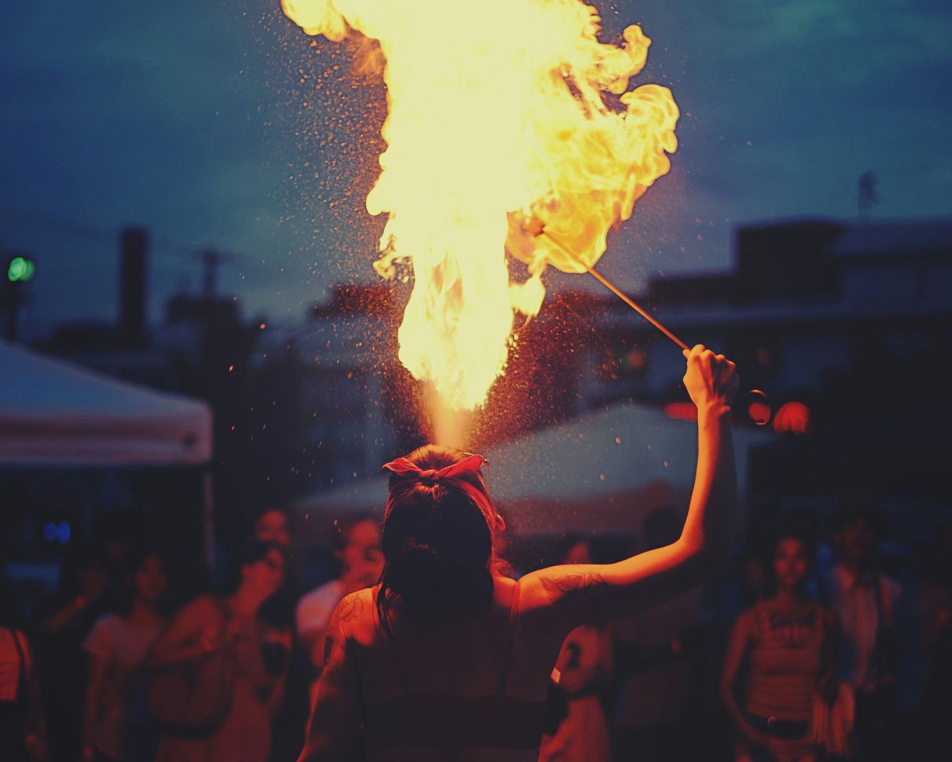 Woman fire breathing infront of a crowd.