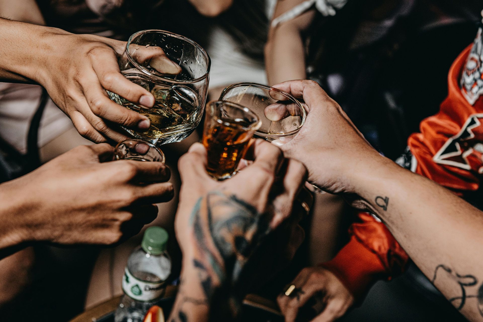 Friends toasting with whiskey glasses at celebration party.