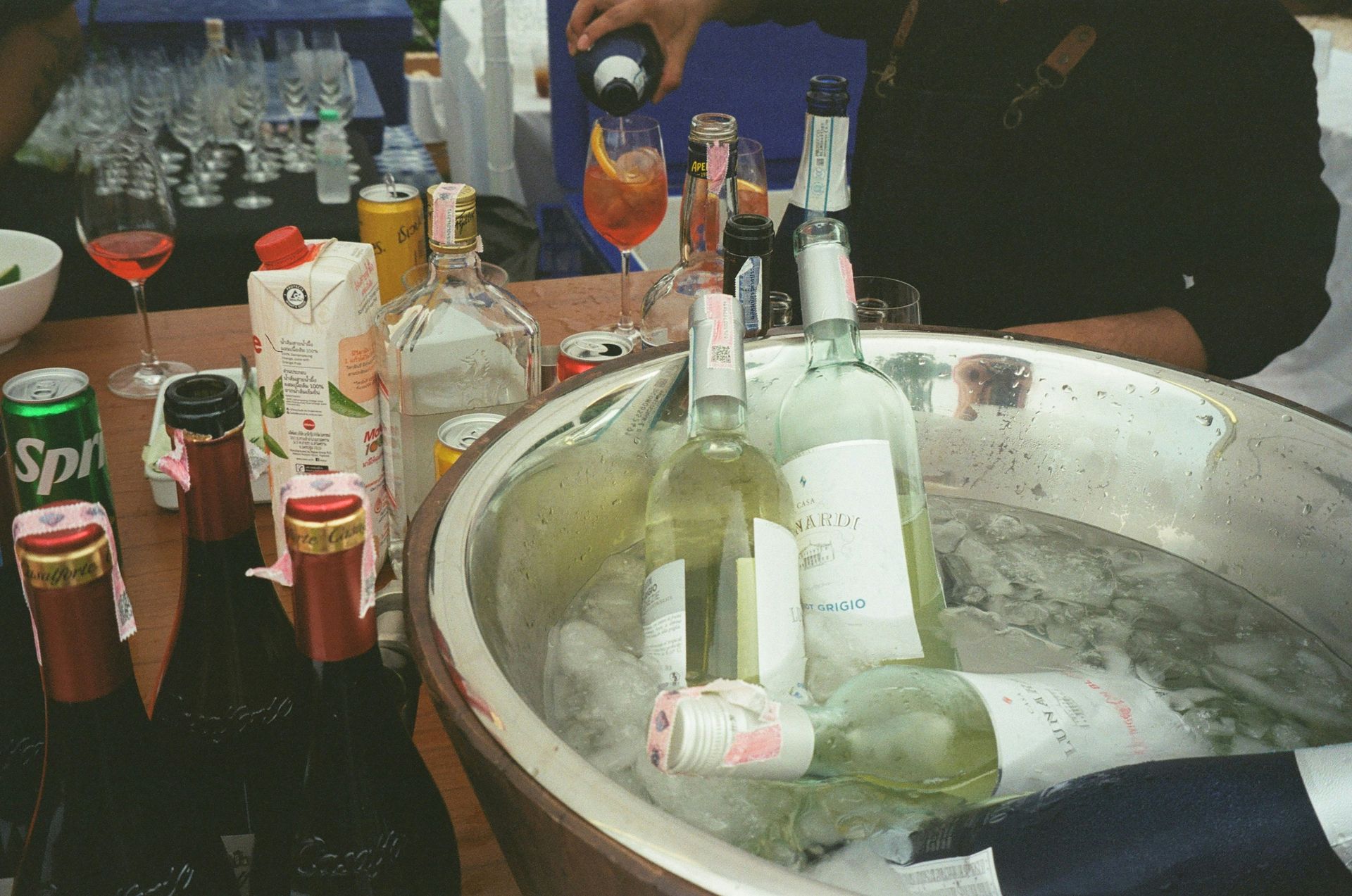 Wine bottles chilling in ice bucket with cocktail glass at party.