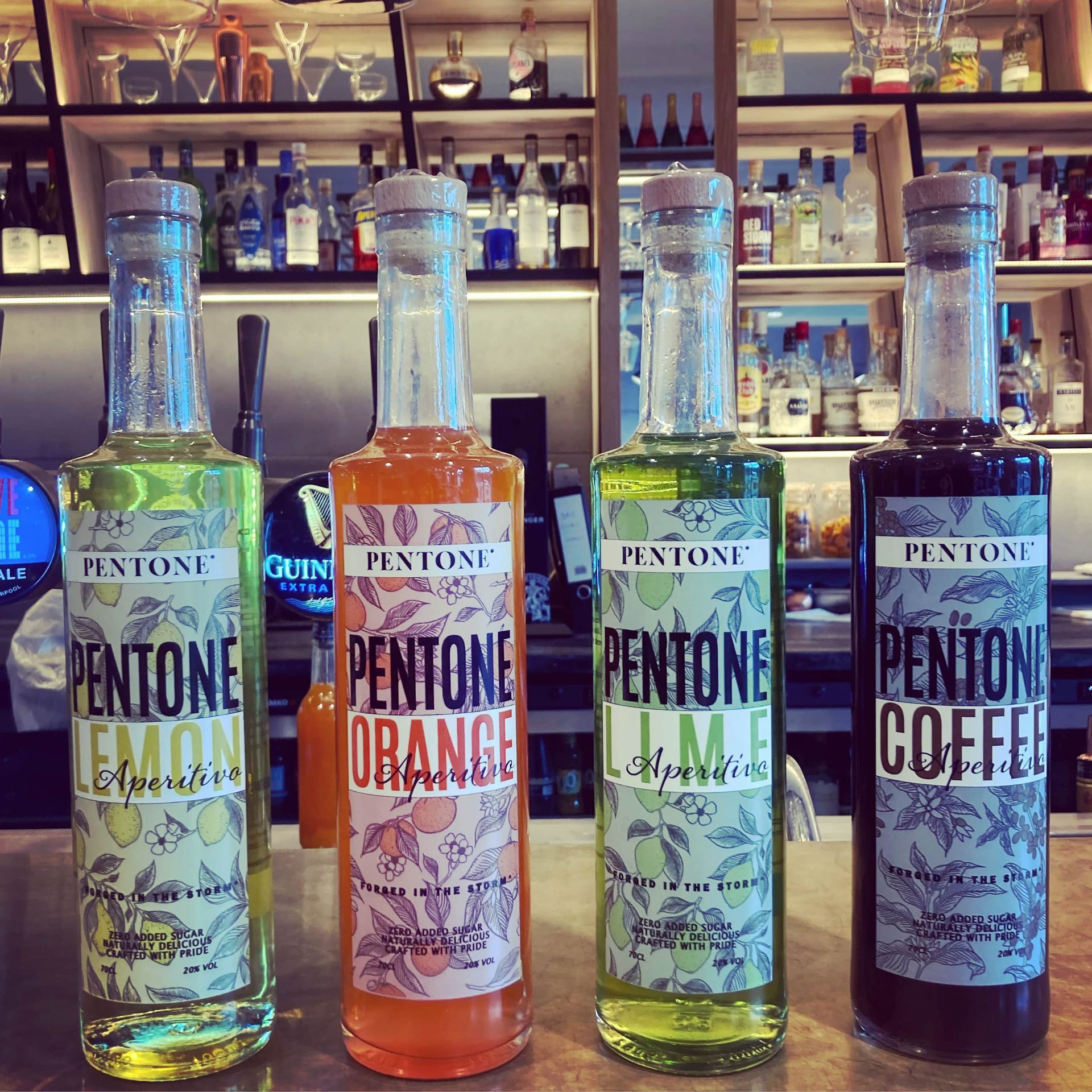 Four bottles of Aperitivo pentone liquors are lined up on a bar in Novotel