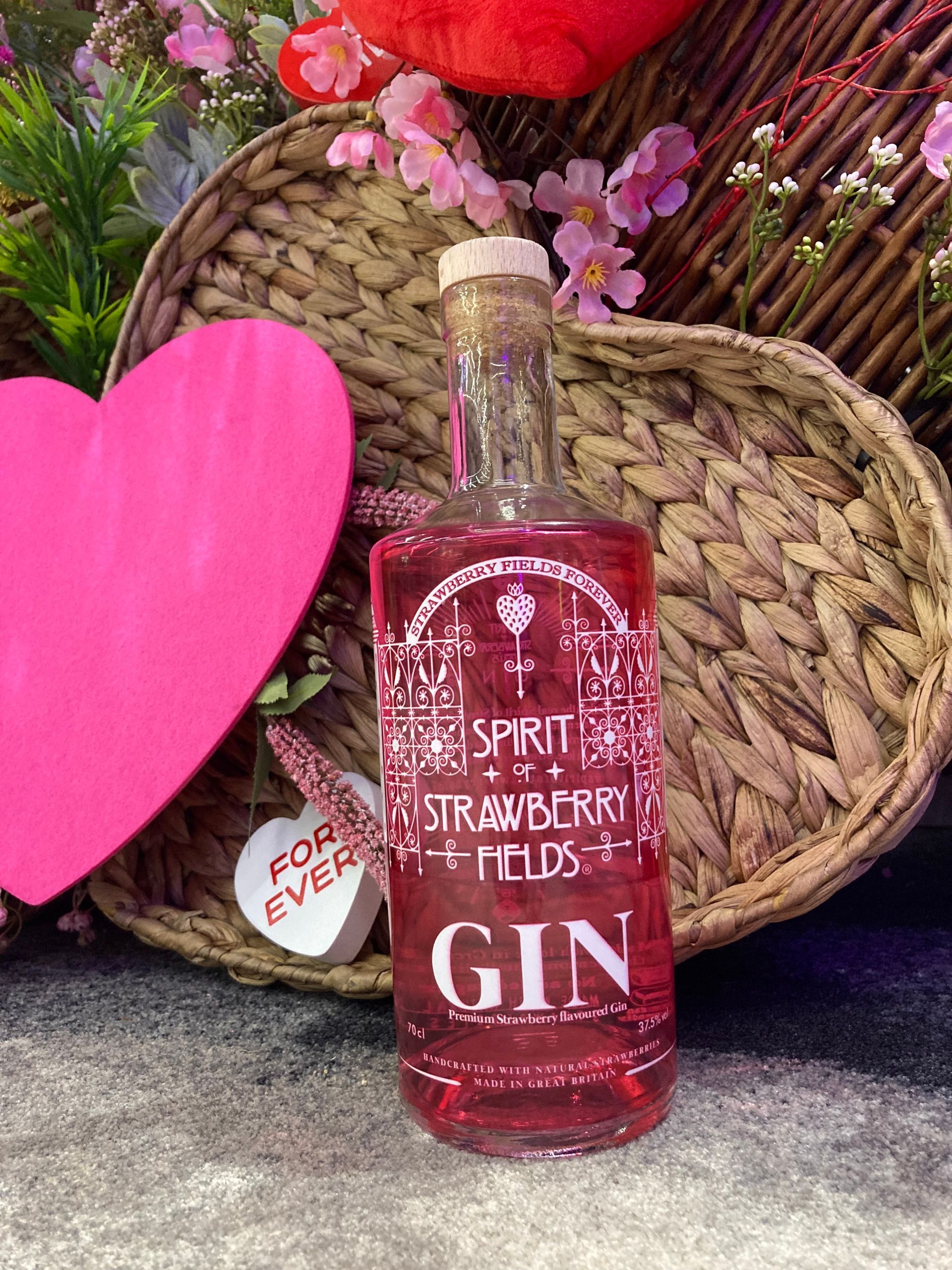 A bottle of Strawberry Fields Gin with a heart, basket and forever love heart