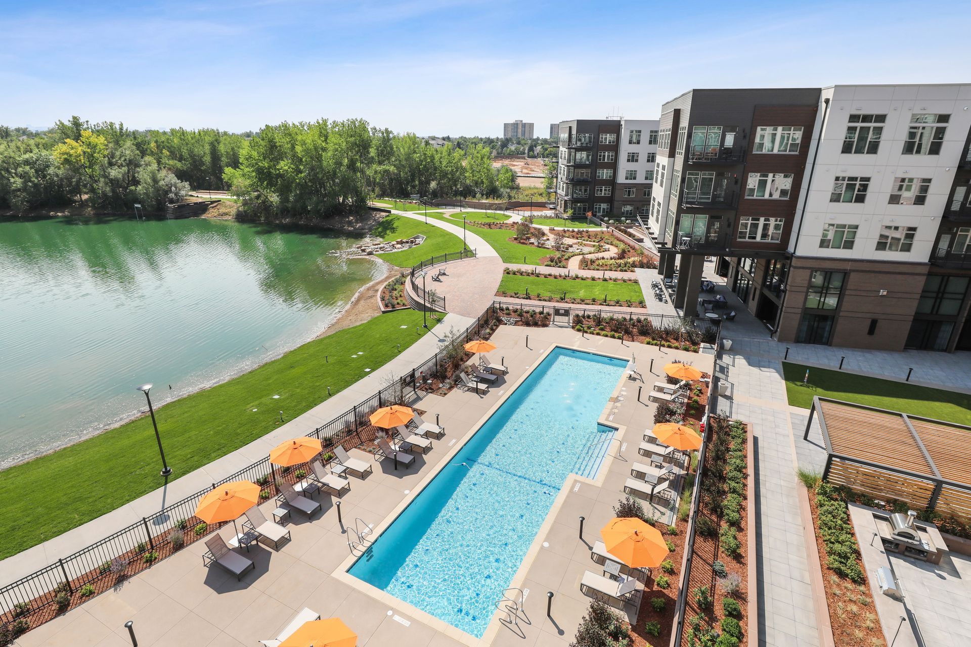 An aerial view of a large swimming pool surrounded by chairs and umbrellas with lake view at Airie in Denver.