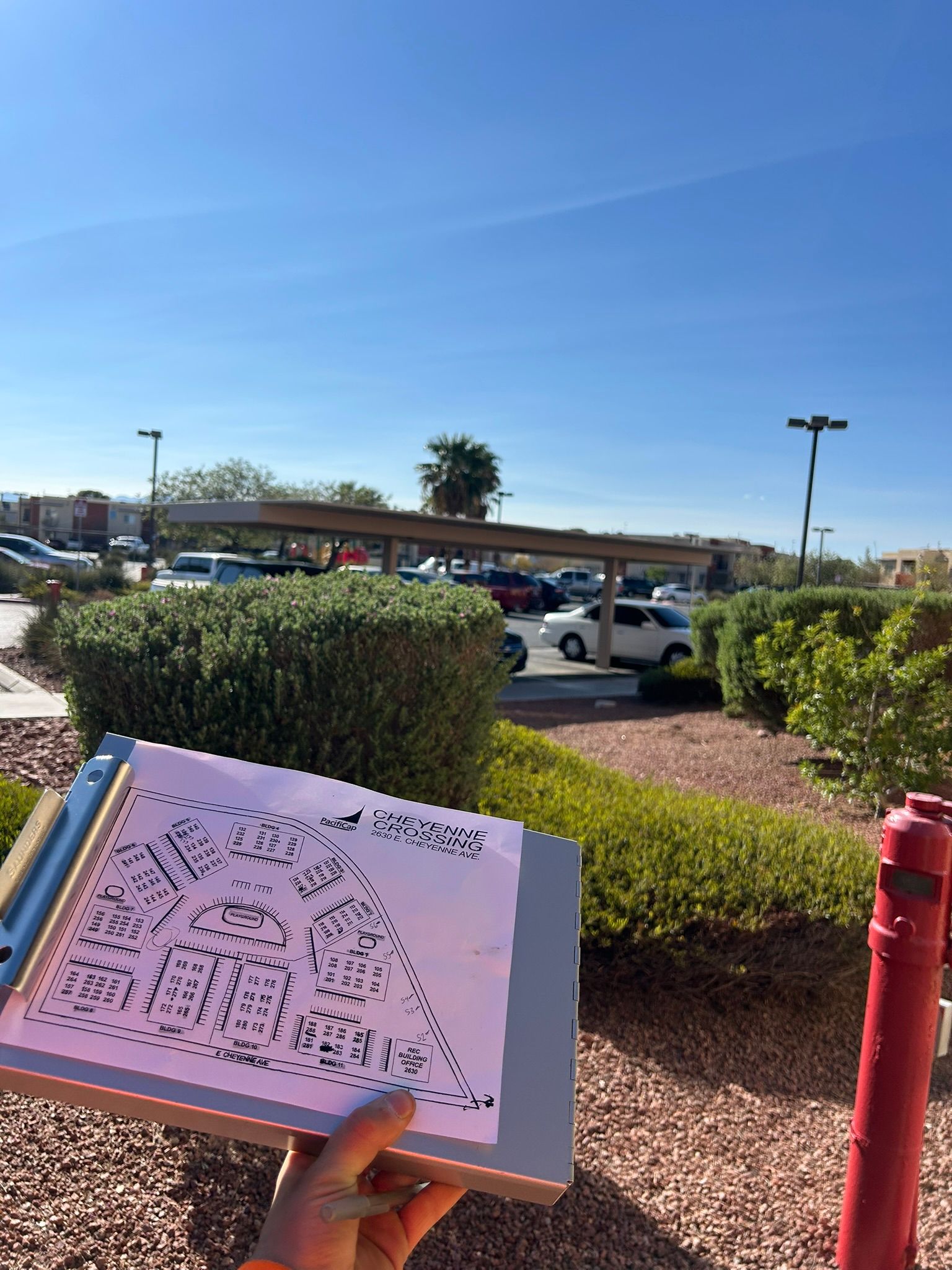 Hand holding a clipboard with a diagram, background view of a parking lot and sunny sky.