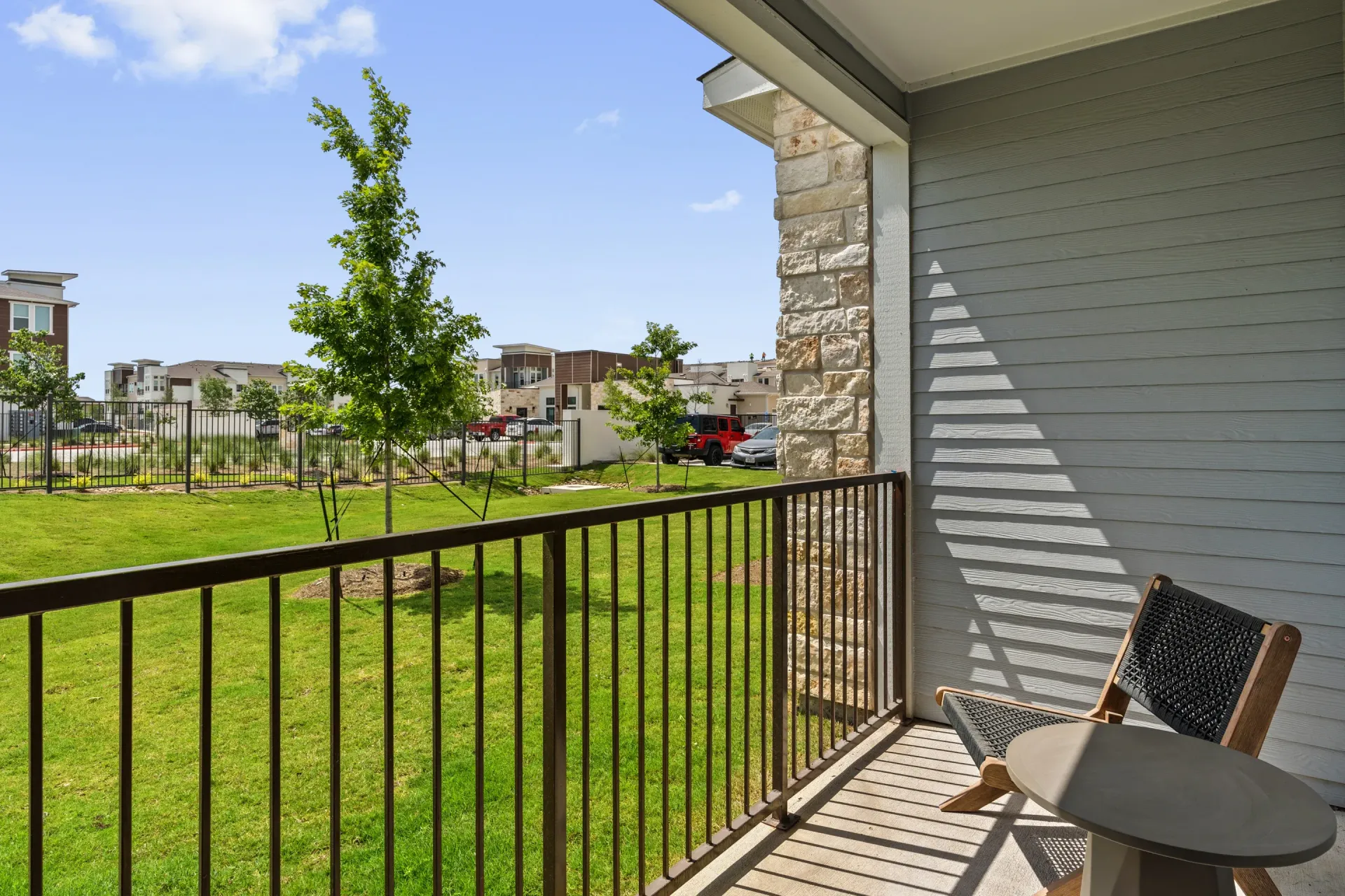 Balcony view with railing overlooking a green lawn and neighboring buildings.