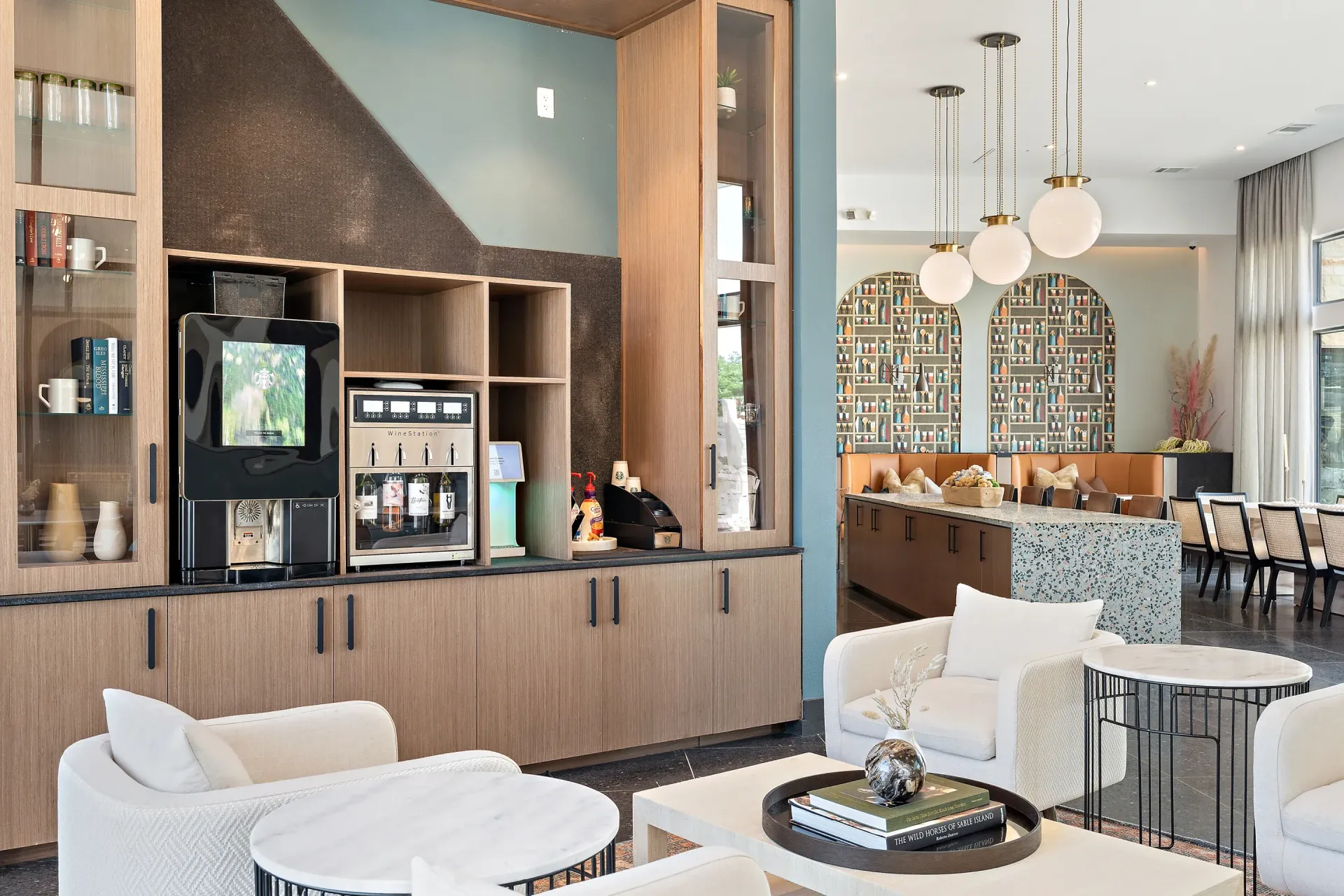 Modern community lounge with coffee station, seating areas, and decorative wall panels.