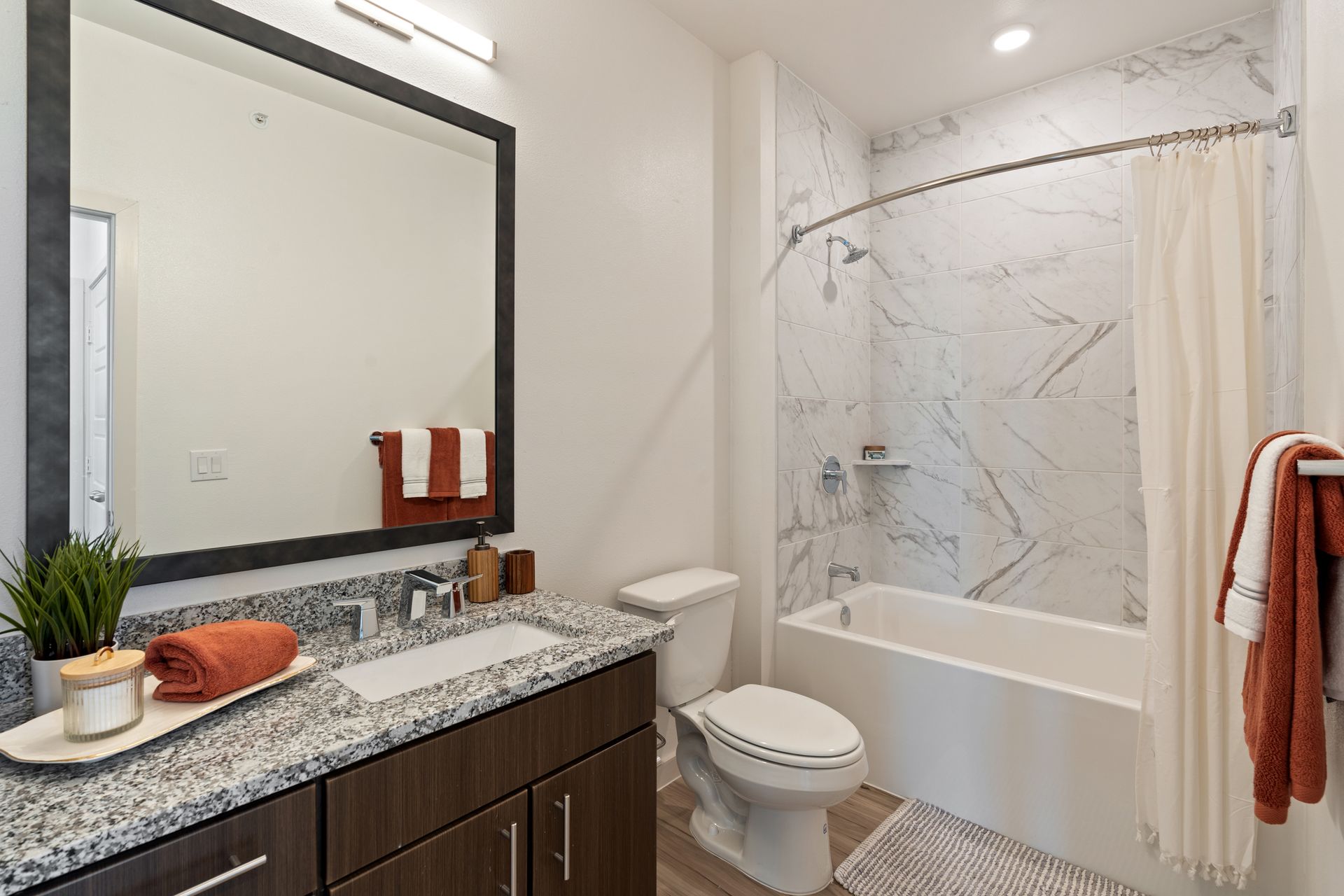 Modern bathroom with marble-tiled shower, granite vanity, and towel rack.