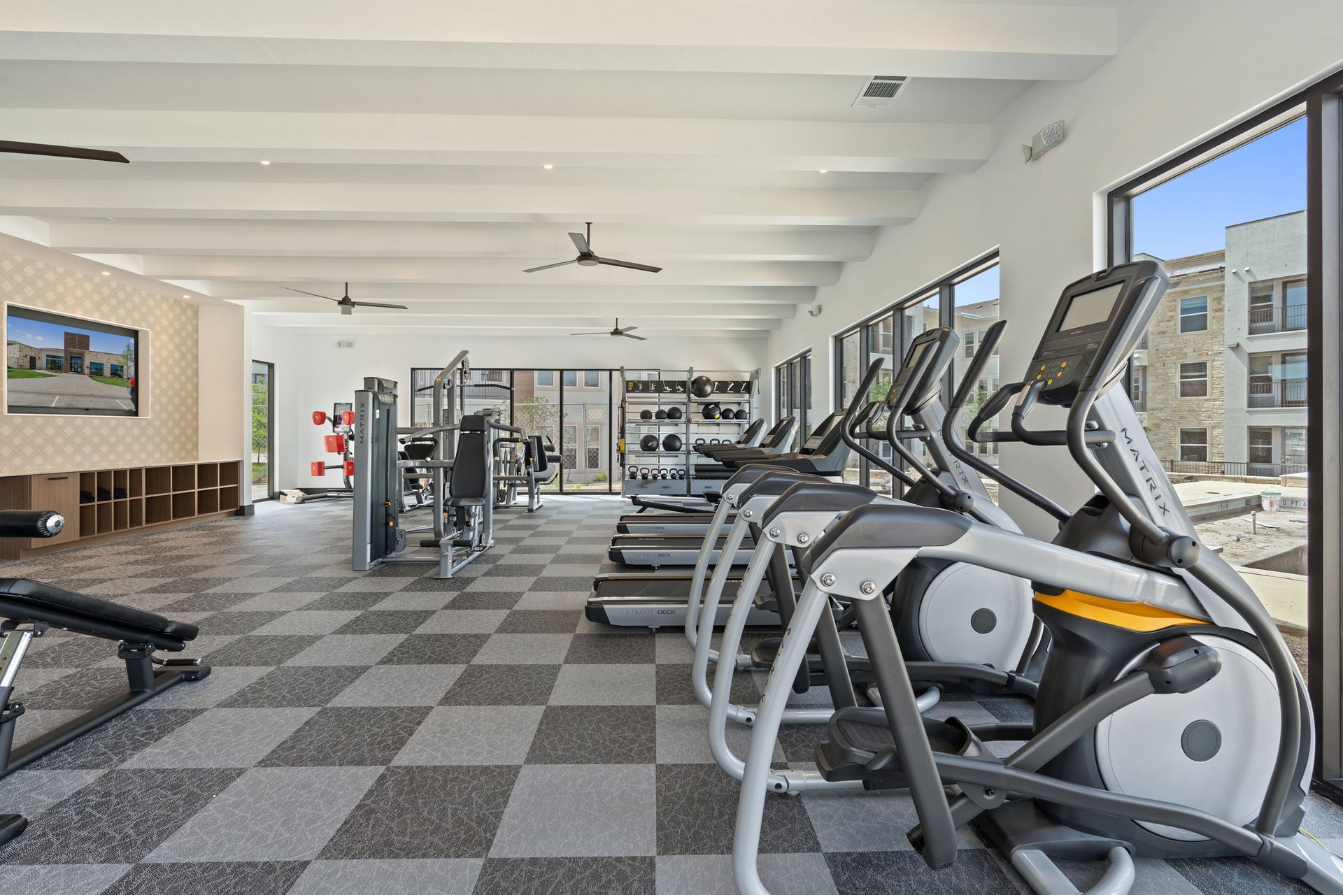 Interior view of a modern apartment gym with cardio machines and weight equipment.