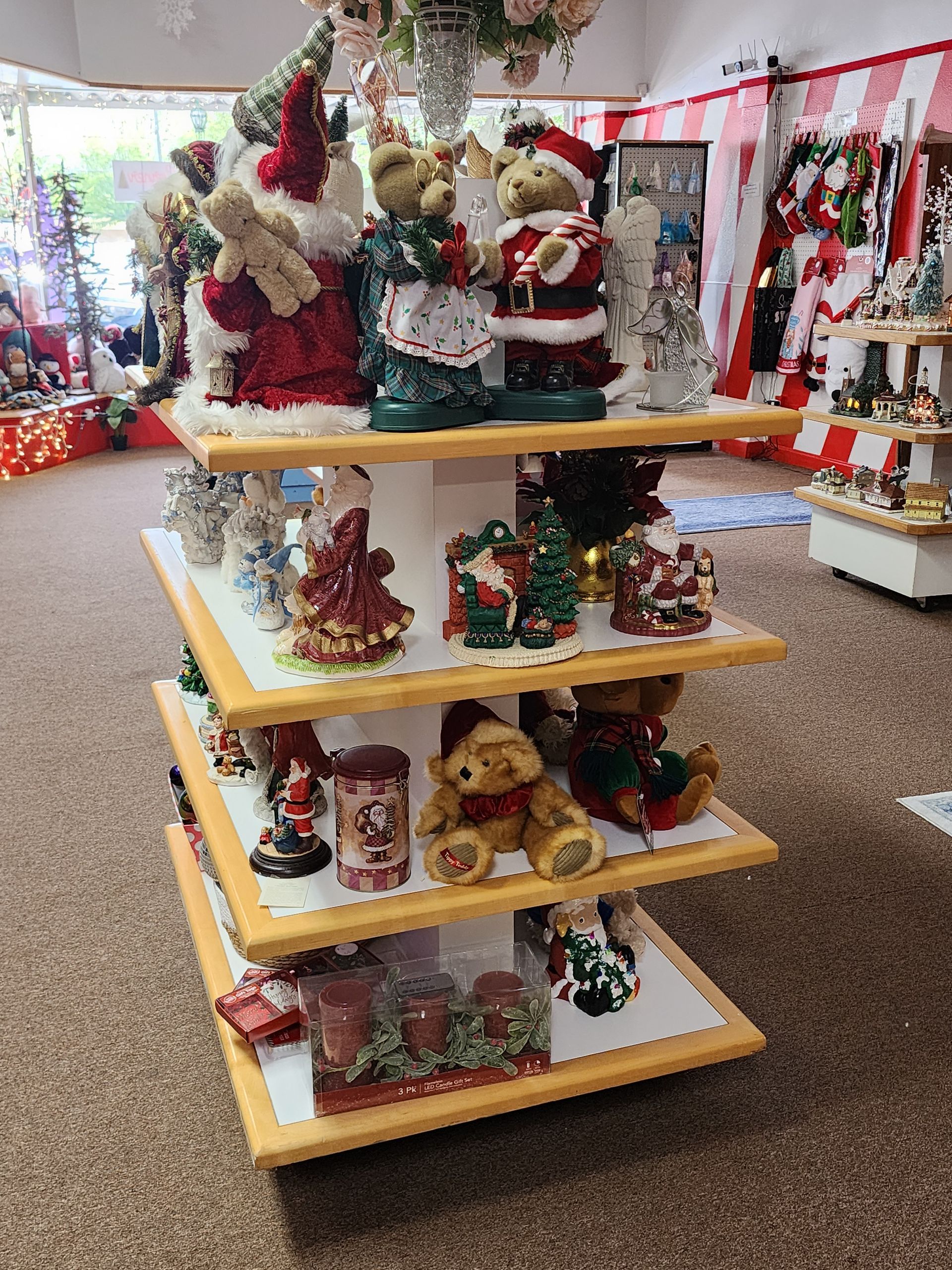 A display of christmas decorations on a wooden shelf in a store.