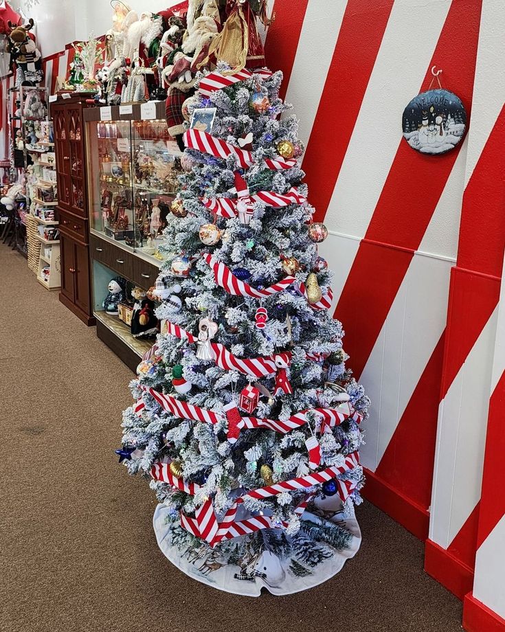 A christmas tree is sitting in front of a red and white striped wall.