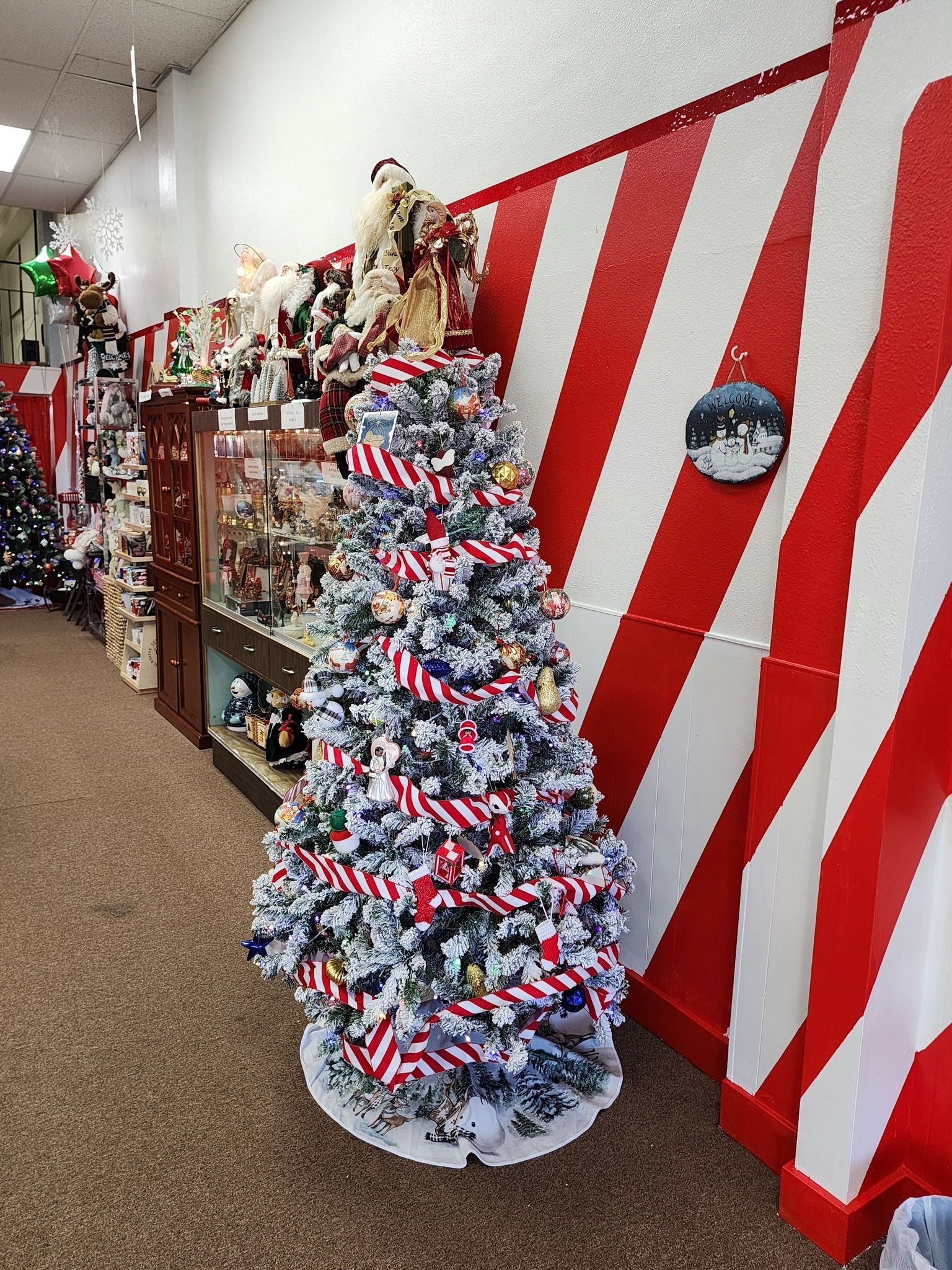A christmas tree is sitting in front of a red and white striped wall.