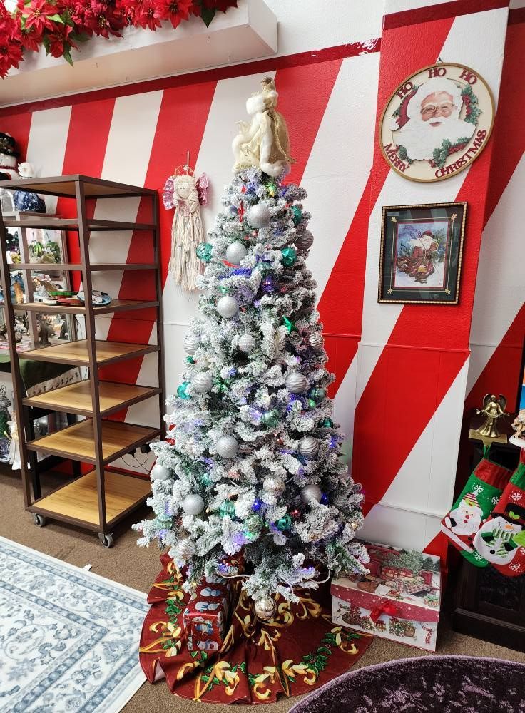 A christmas tree is sitting in front of a red and white striped wall.