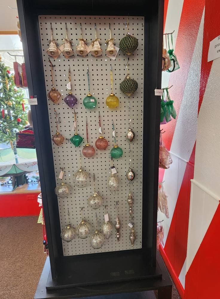 A display of christmas ornaments in a store with a christmas tree in the background.