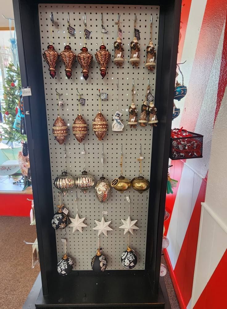 A display of christmas ornaments in a store with a christmas tree in the background.
