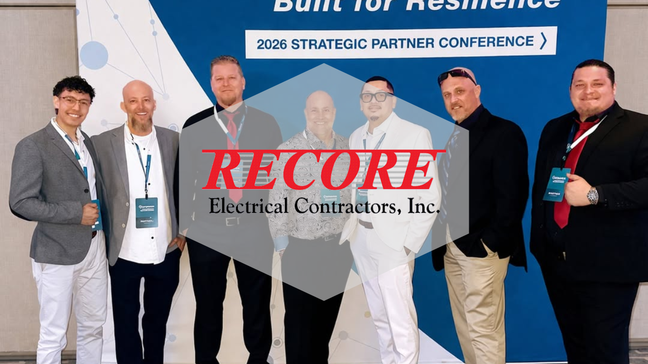 Five men posing at a conference booth holding a Recore Electrical Contractors sign