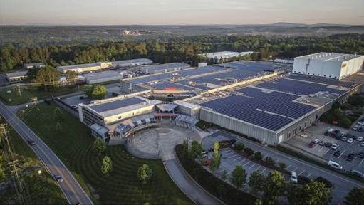 An aerial view of a large building with solar panels on the roof.