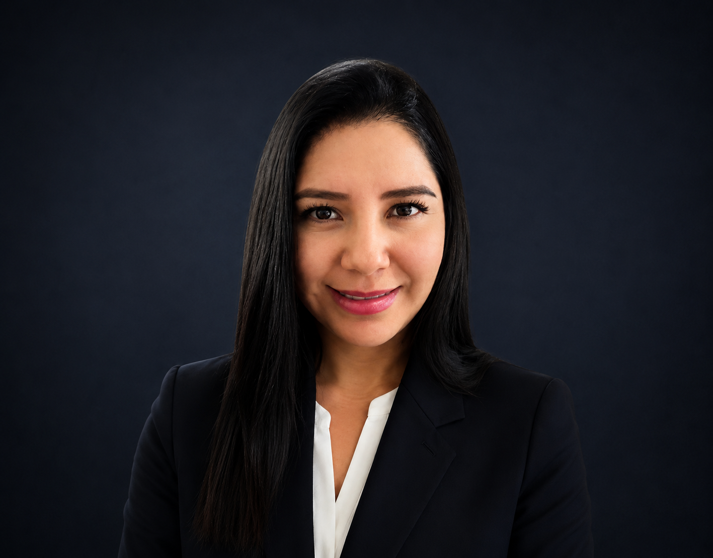 Studio portrait of a smiling woman with long dark hair, wearing a black blazer on a dark background