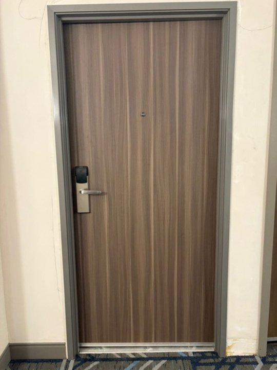 Wooden apartment door with a silver handle and black lock in a hallway