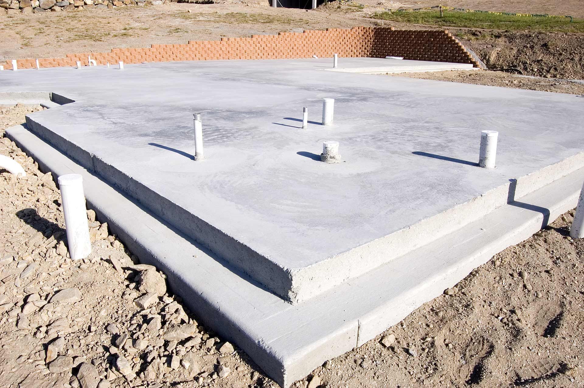A concrete foundation is being built in a dirt field