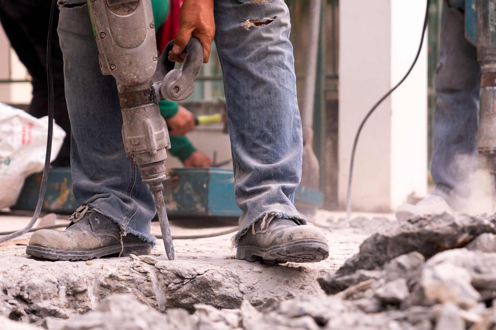 A man is using a hammer to drill a hole in the ground.