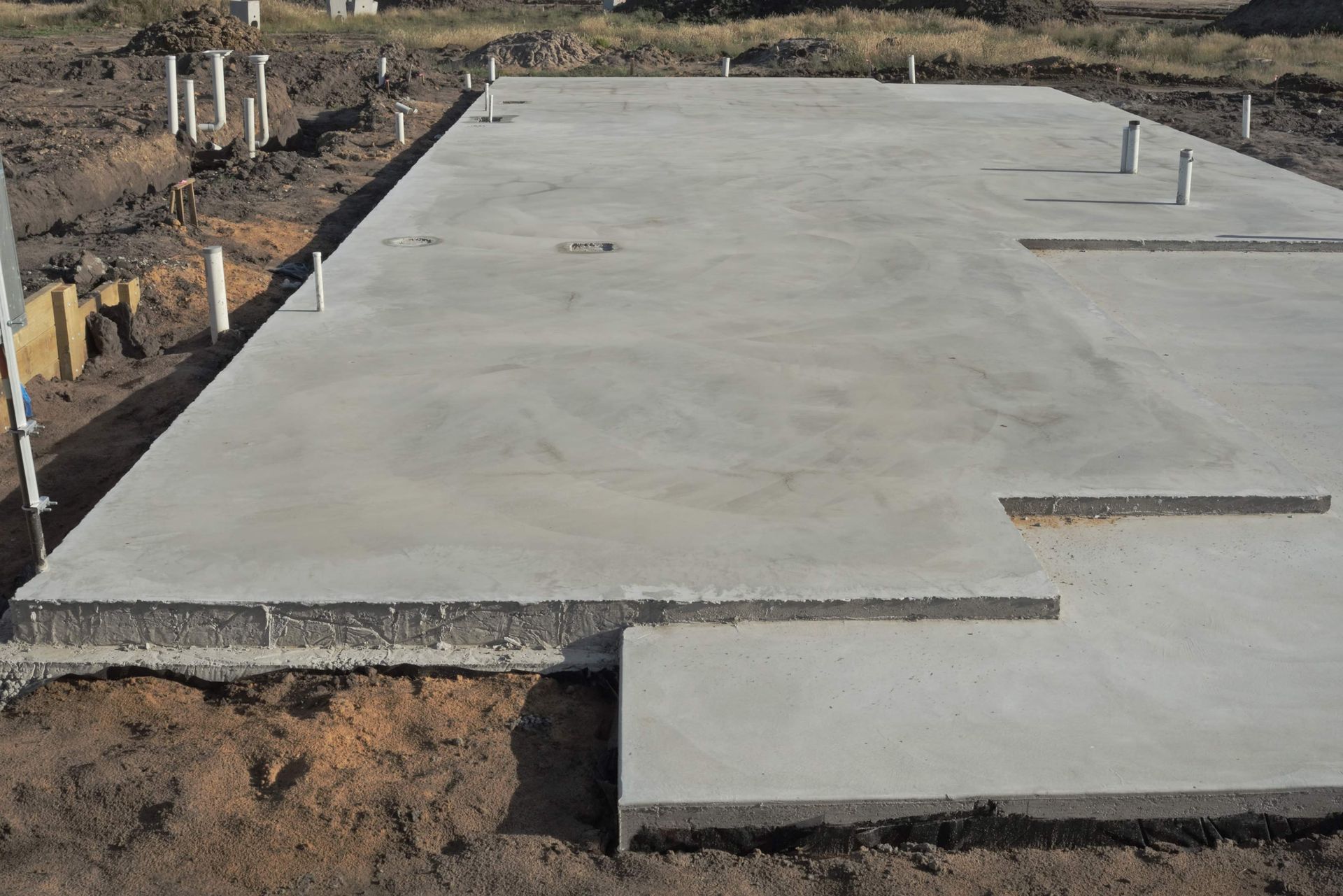 A large concrete slab is sitting on top of a dirt field.