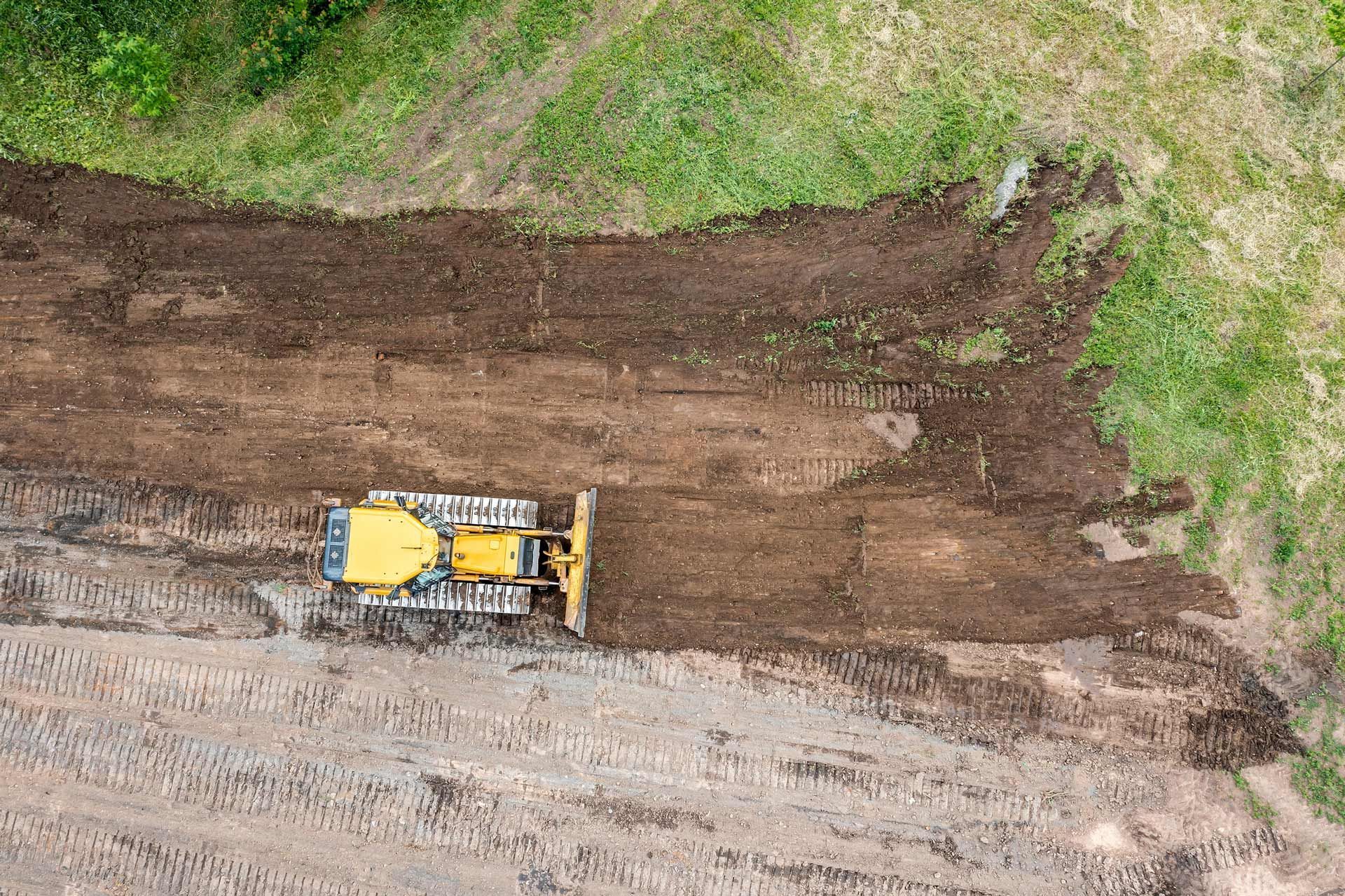 An aerial view of a bulldozer working on a dirt road.