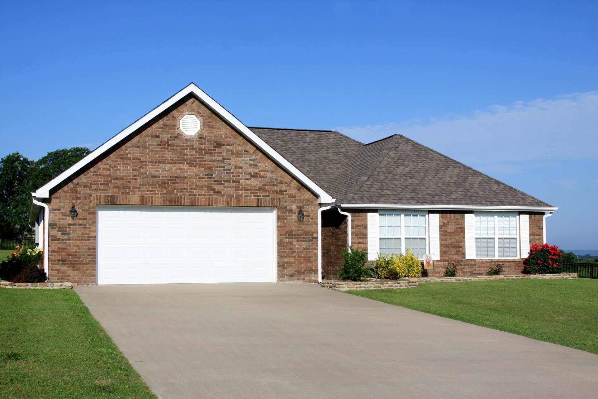 A brick house with a white garage door and a driveway
