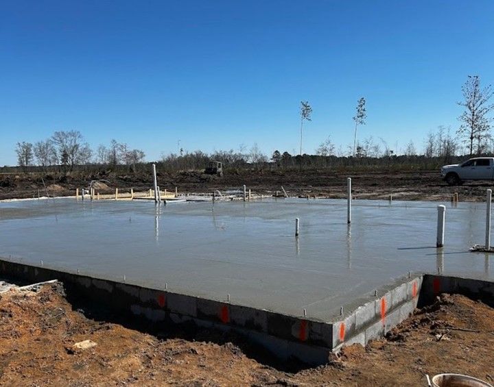 A concrete foundation is being built on a dirt field.