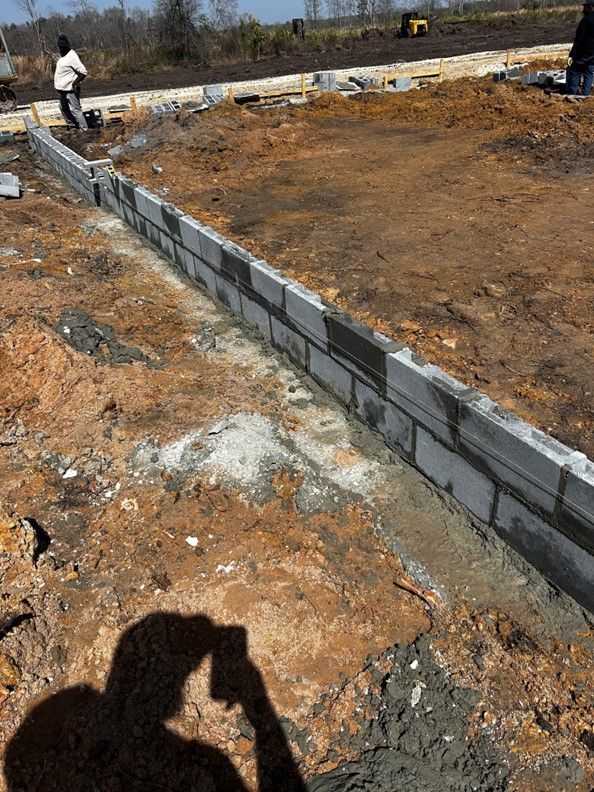 A person is taking a picture of a brick wall being built.